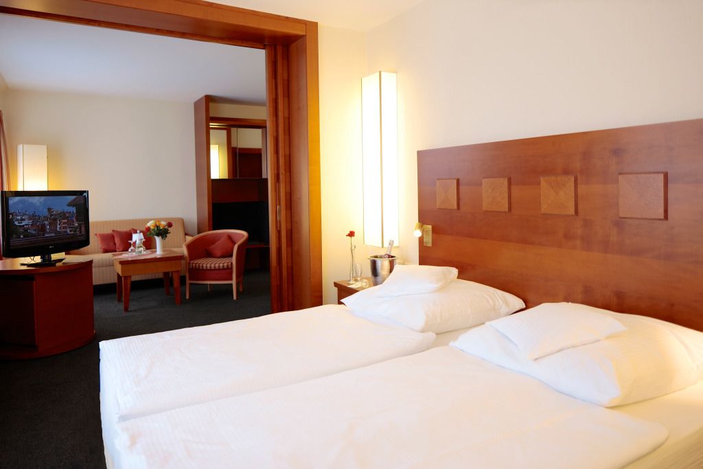 Una habitación de hotel con dos camas, televisión, escritorio y una silla.