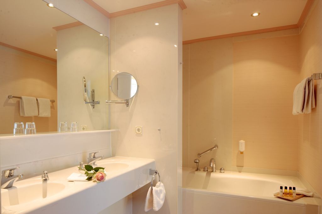 Un baño con dos lavamanos, un espejo grande, una bañera y un perchero para toallas.