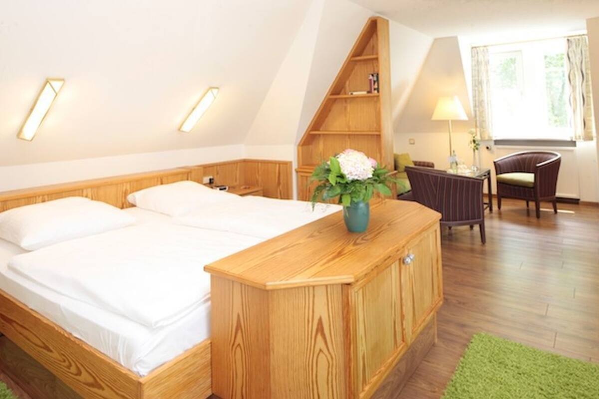 A bedroom with a wooden bed, a desk, a chair, and a small shelving unit.