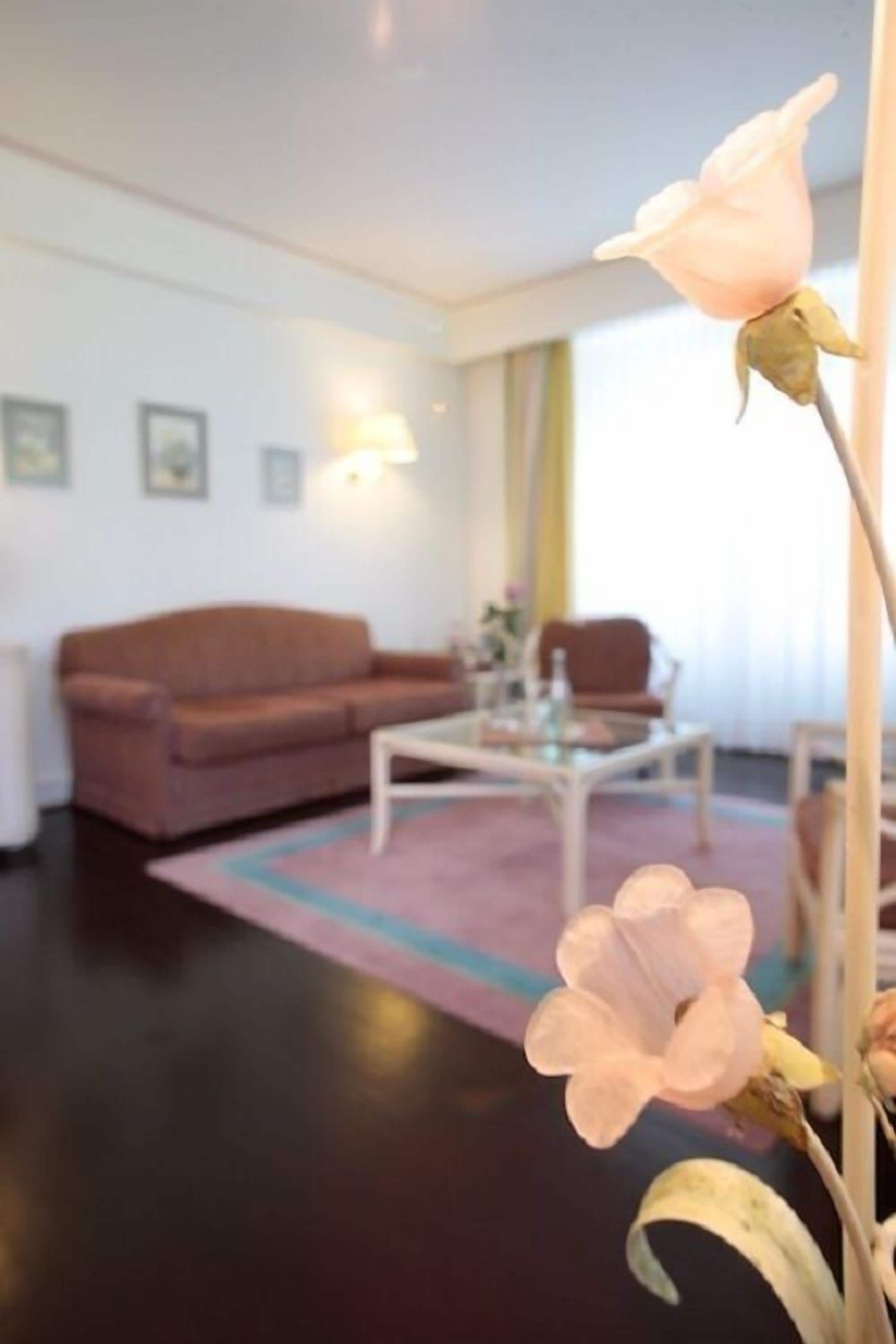 Una sala de estar con sofá, mesa de centro y un arreglo floral.
