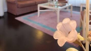 En opholdsstue med sofa, sofabord og blomsterarrangement.