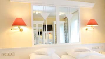 Habitación de hotel con dos camas, un ventanal con vistas y lámparas de pared.
