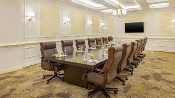 A conference room with a long table, multiple chairs, and a flat-screen TV on the wall.