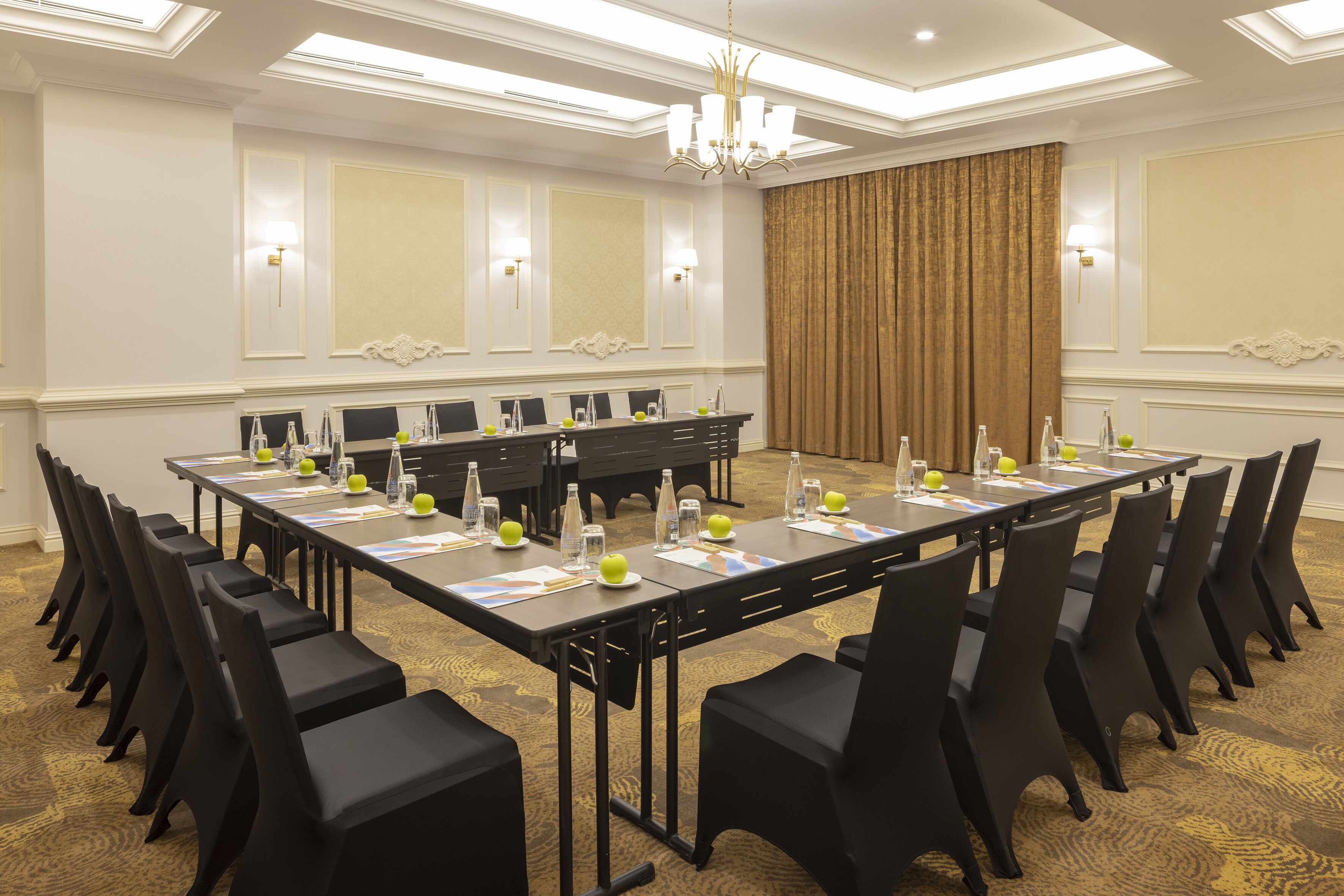 A conference room with a long table, black chairs, and a chandelier.