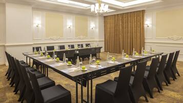 A conference room with a long table, black chairs, and a chandelier.