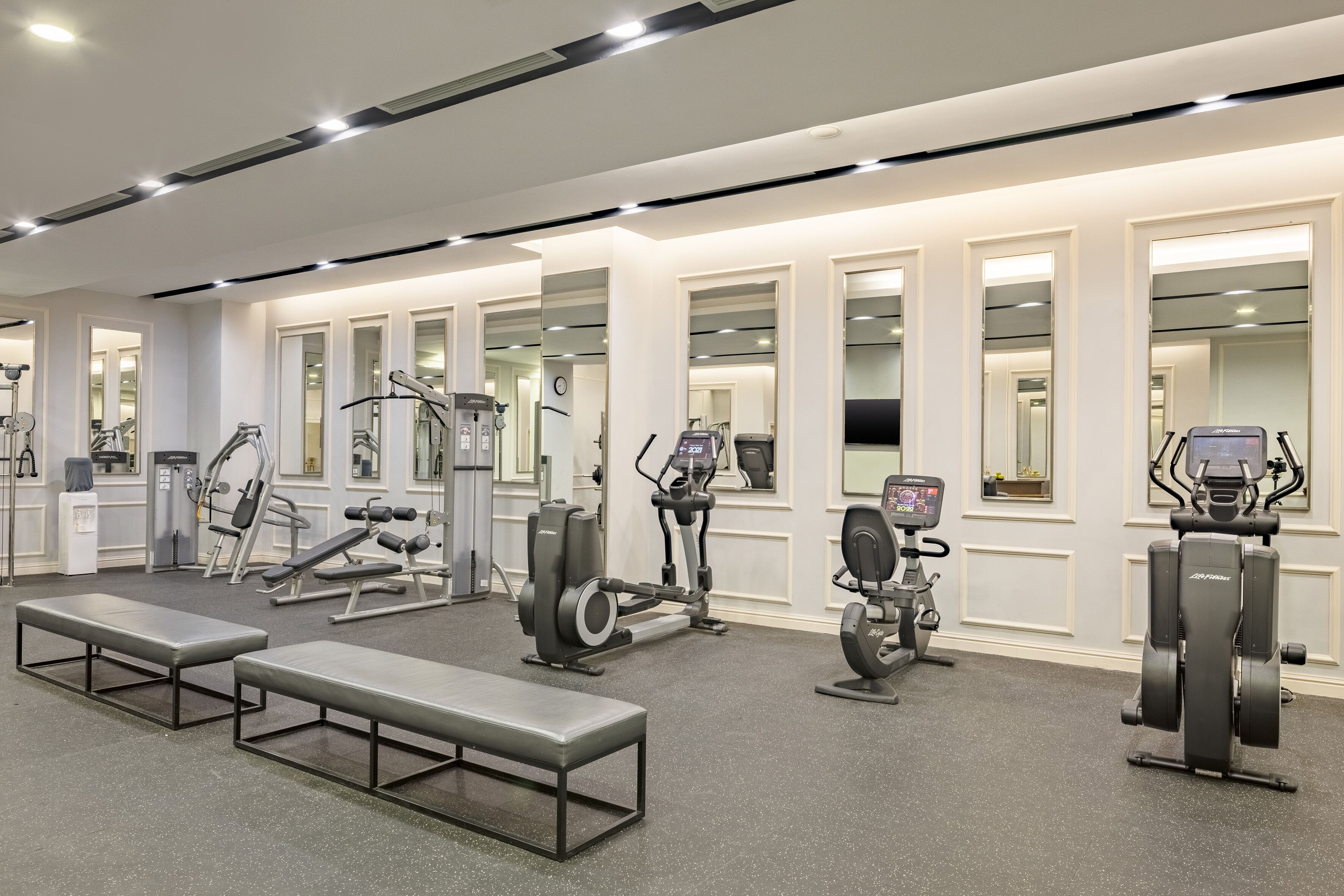 A modern gym with various exercise equipment, including treadmills, stationary bikes, and weight machines.
