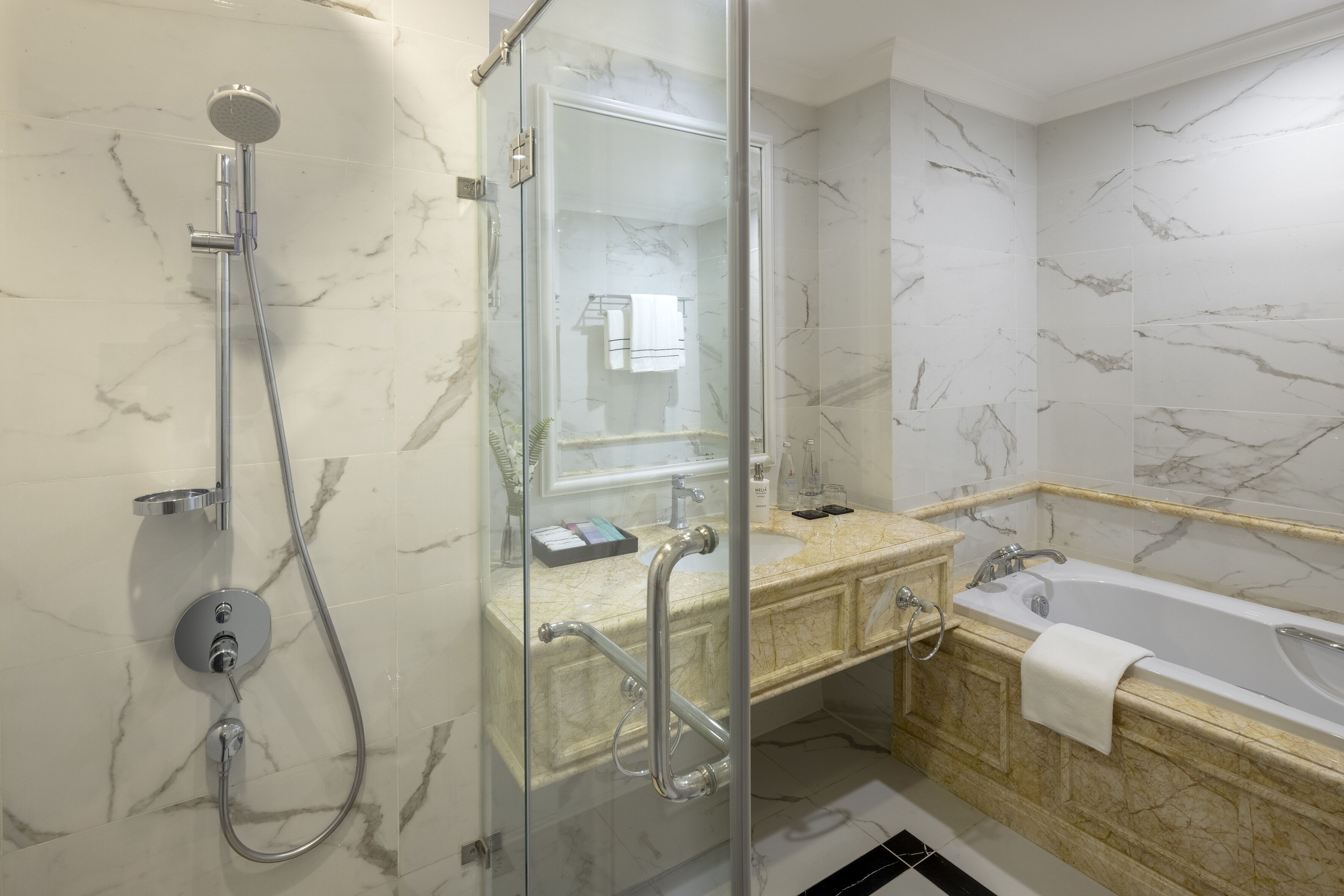 Un baño moderno con ducha de vidrio, tocador con azulejos de mármol y bañera.