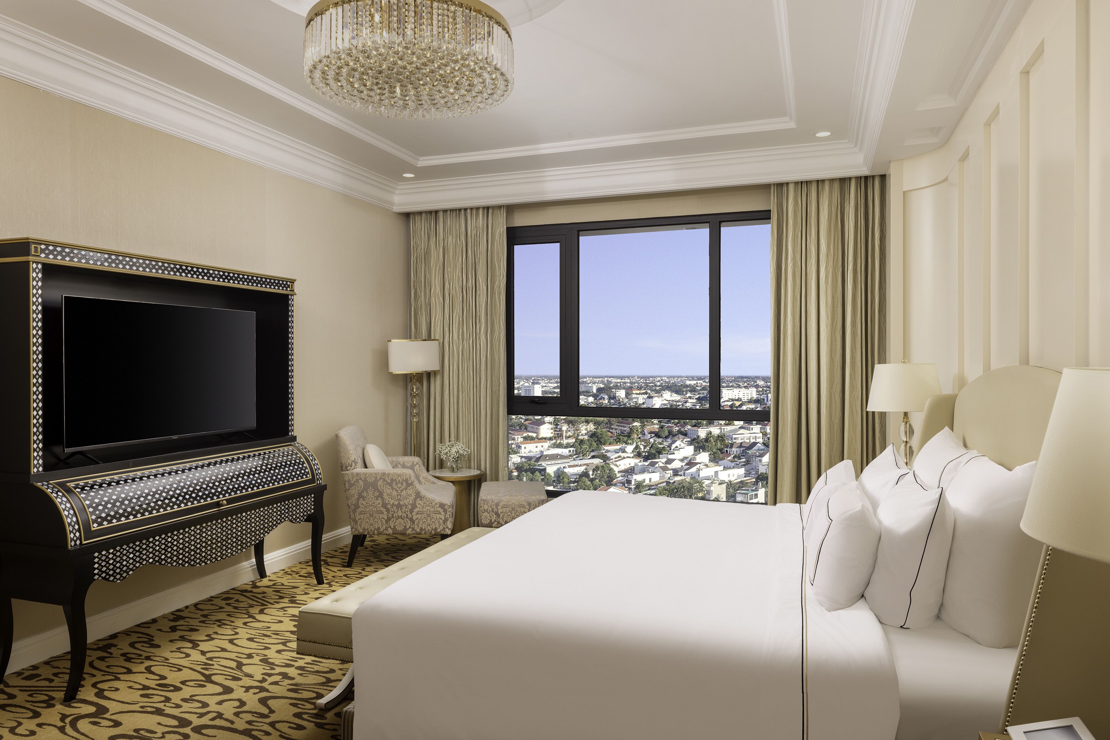 Ein Hotelzimmer mit einem großen Bett, einem Fernseher, einem Klavier und Blick auf die Stadt.