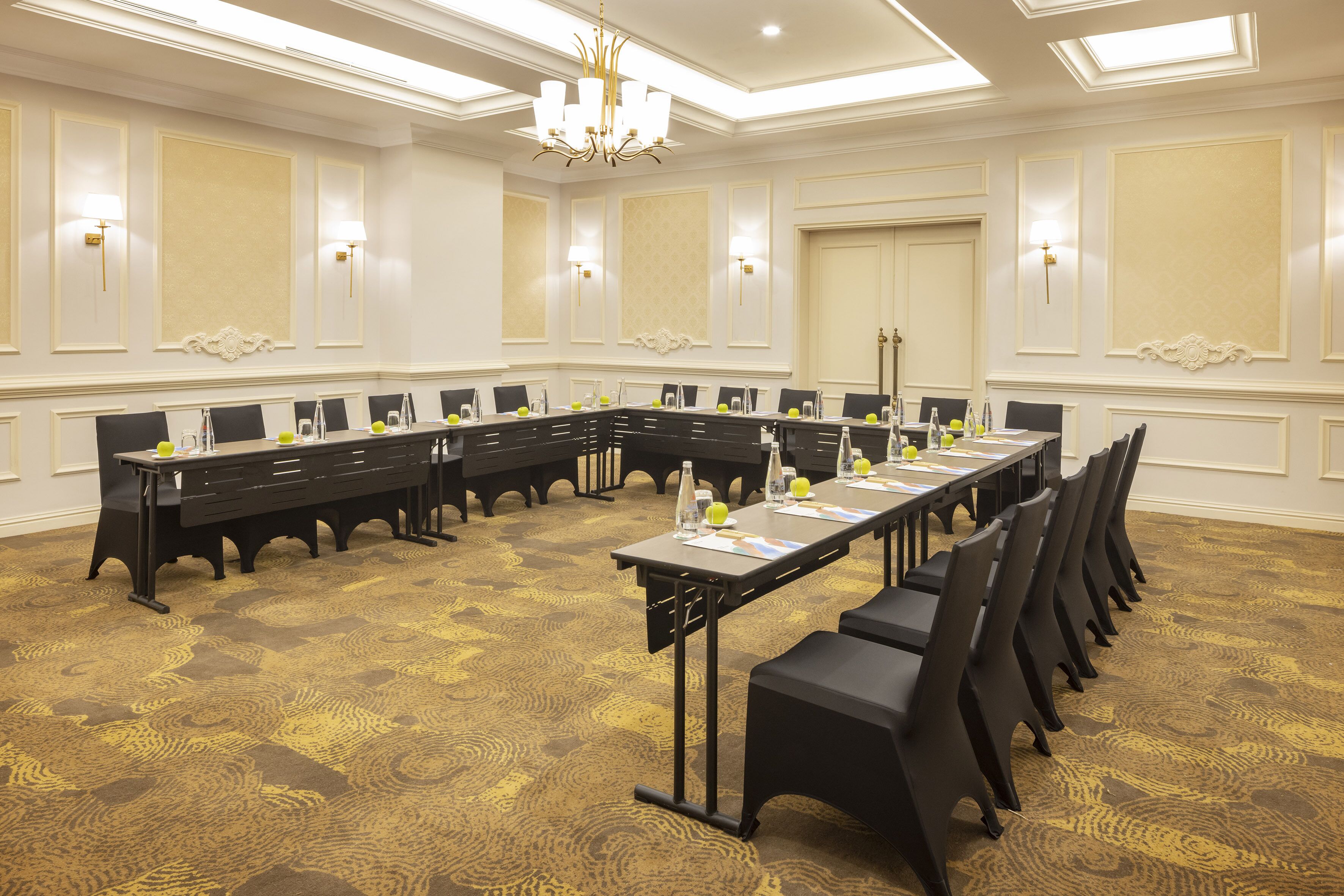 A conference room with a long table, black chairs, and a chandelier.