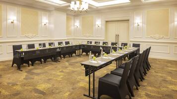 A conference room with a long table, black chairs, and a chandelier.