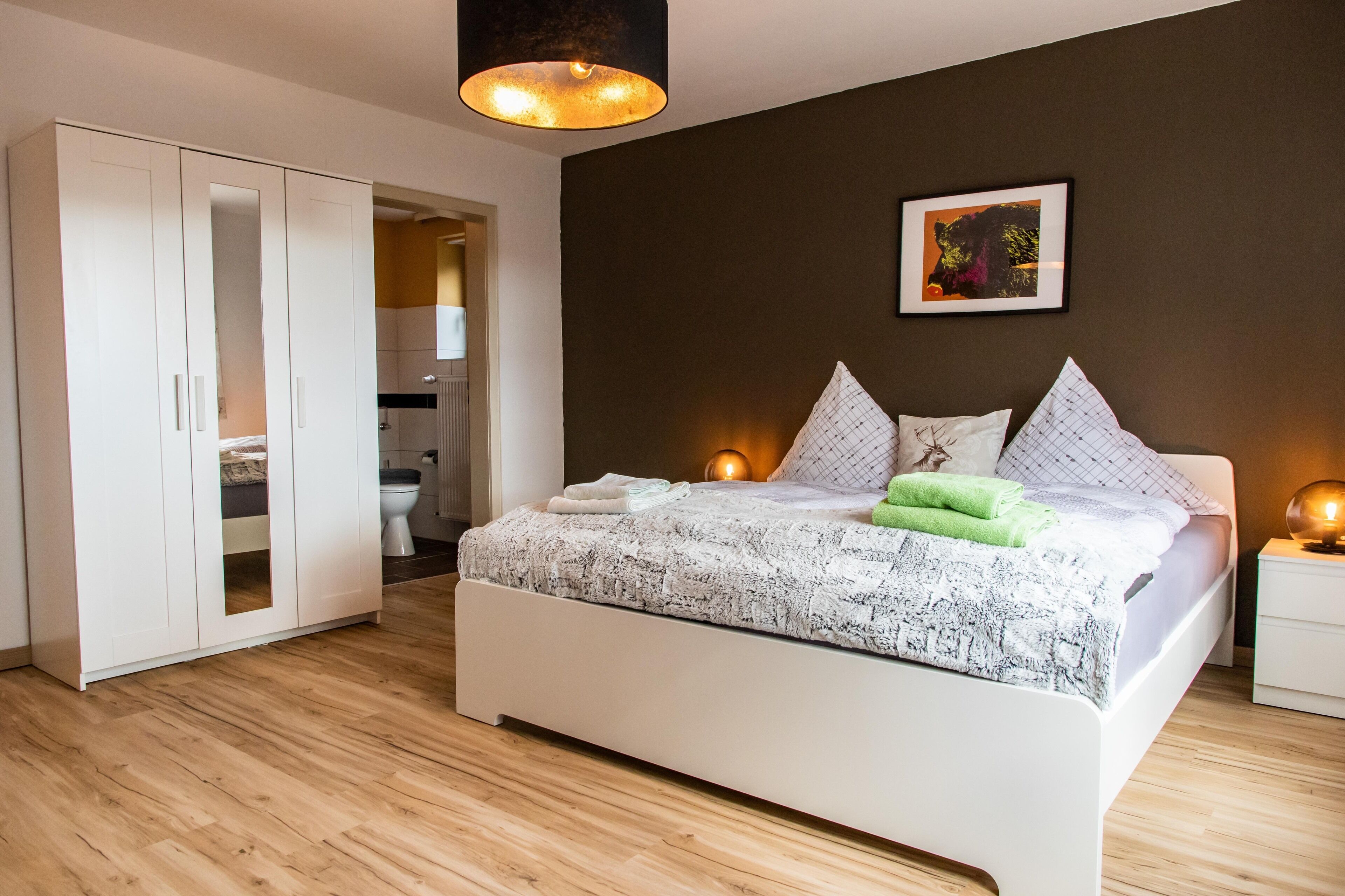 Ein Schlafzimmer mit Bett, weißem Kleiderschrank und angrenzendem Badezimmer.