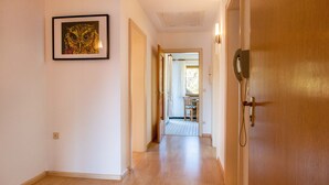 Un couloir doté d’un plancher en bois, une œuvre d’art encadrée au mur et une porte avec un téléphone.