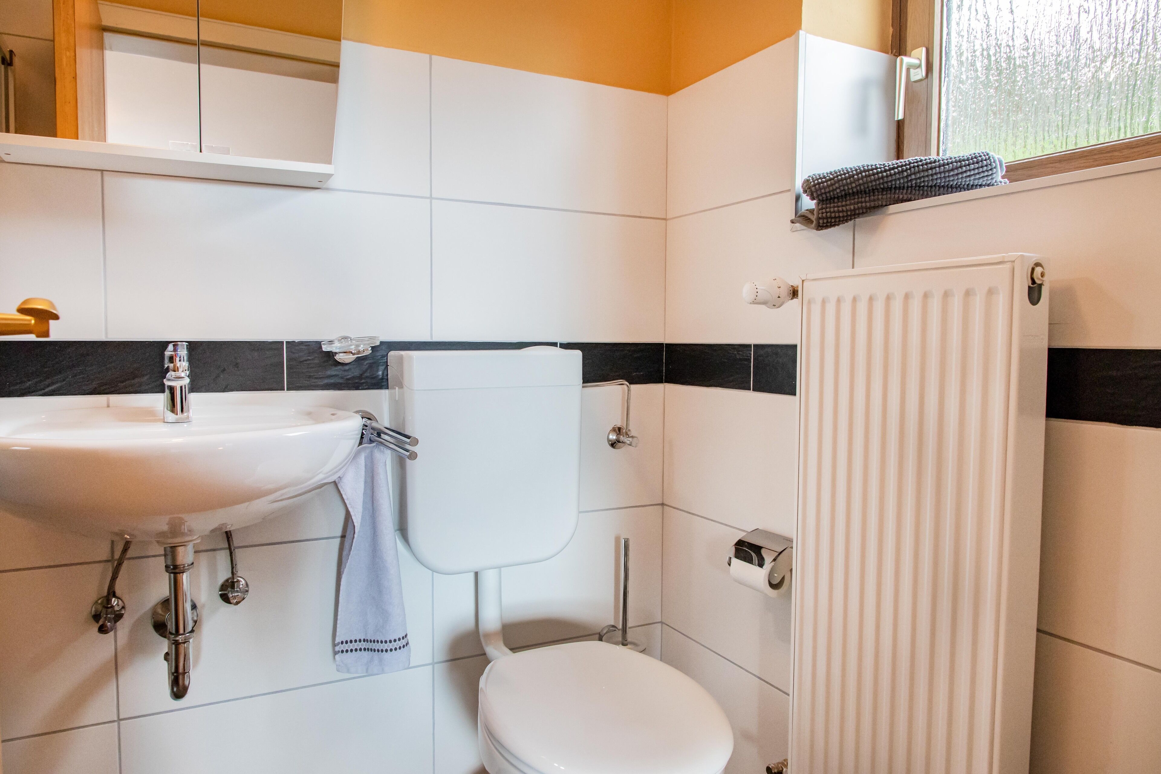 A bathroom with a white sink, toilet, and radiator.