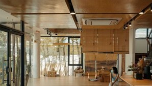 Una cocina moderna con armarios de madera, una zona de bar con taburetes y un amplio ventanal que proporciona luz natural.