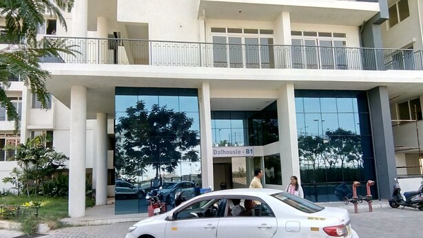 A multi-story building with a modern architectural design, featuring large windows and a central entrance. - TripThrill Maytas Hill Apartments (Hyderabad)