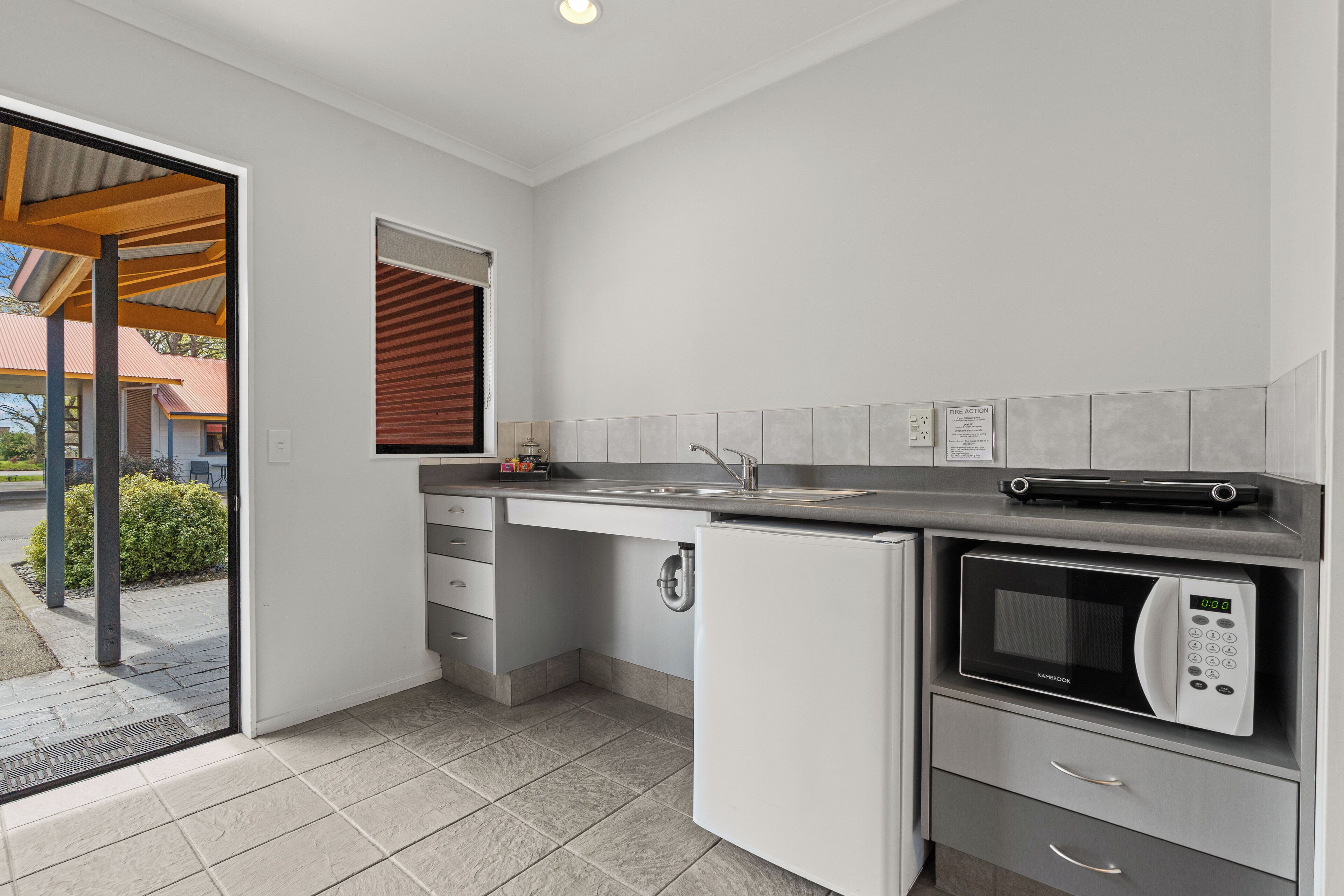 A compact kitchen with a built-in microwave, a sink, and a small refrigerator.