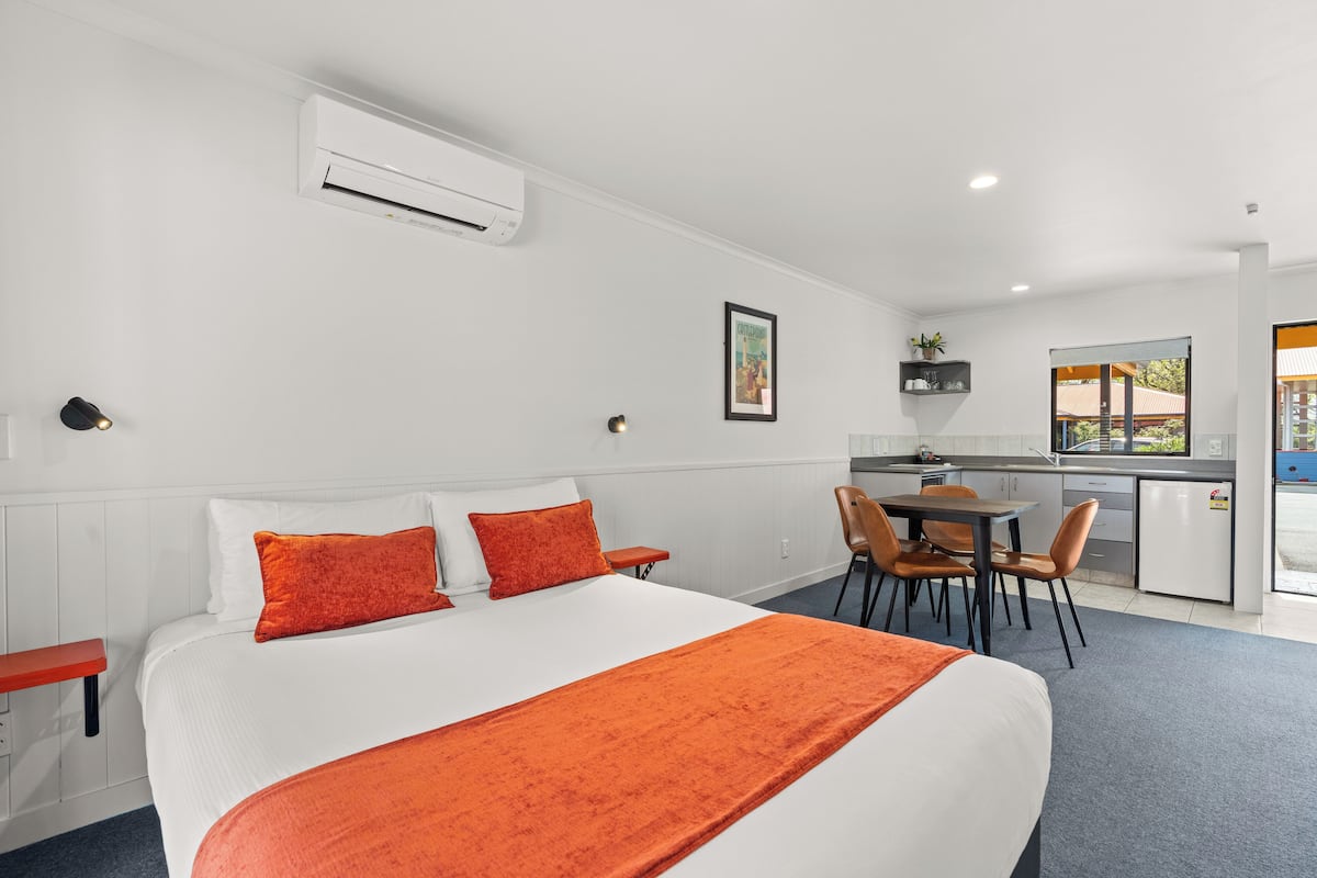 A hotel room with a bed, a desk, and a kitchenette.