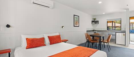A hotel room with a bed, a desk, and a kitchenette.