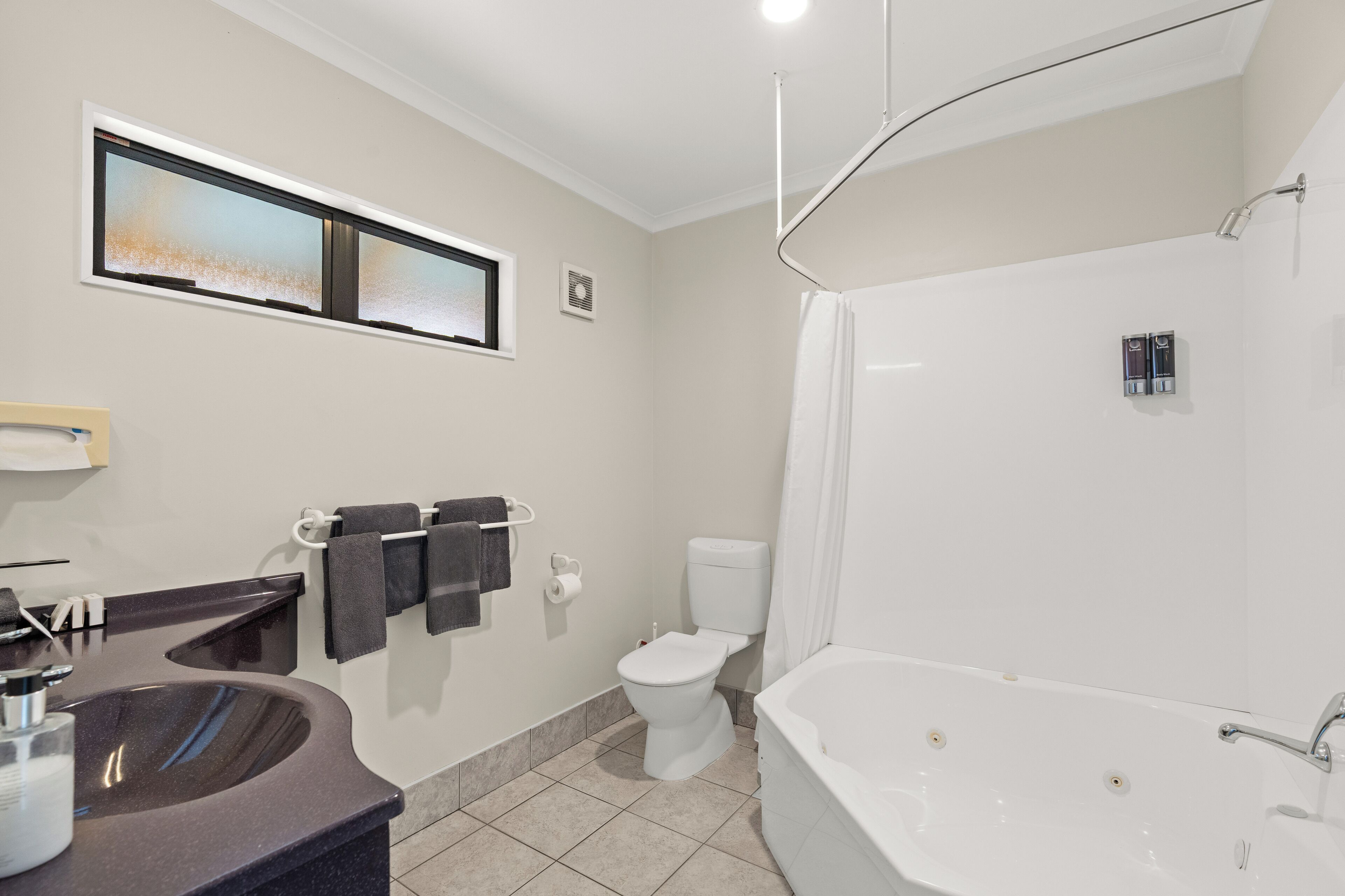 A modern bathroom with a sink, toilet, and bathtub.
