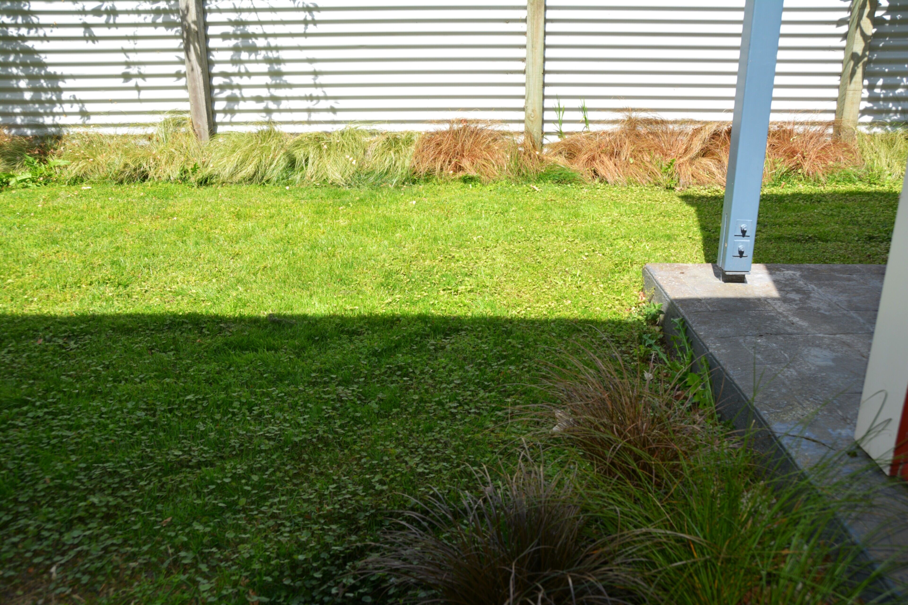 A well-maintained grassy area with a concrete pathway and a metal pole.