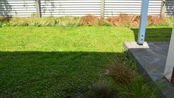 A well-maintained grassy area with a concrete pathway and a metal pole.