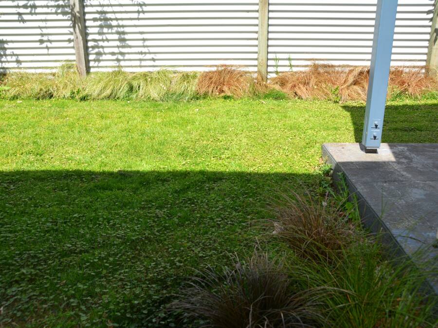 A well-maintained grassy area with a concrete pathway and a metal pole.