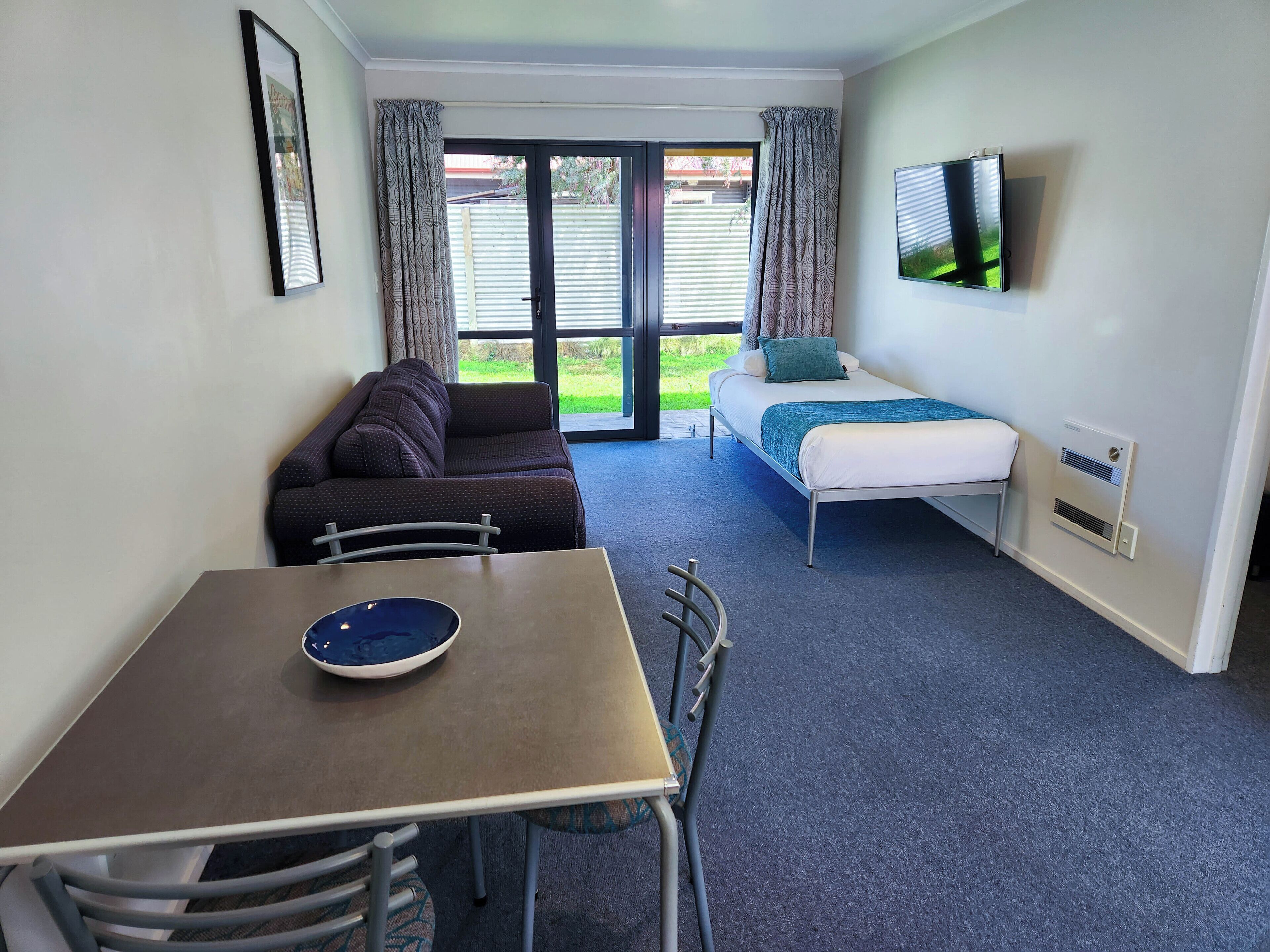 A room with a bed, a sofa, a table, and a TV.