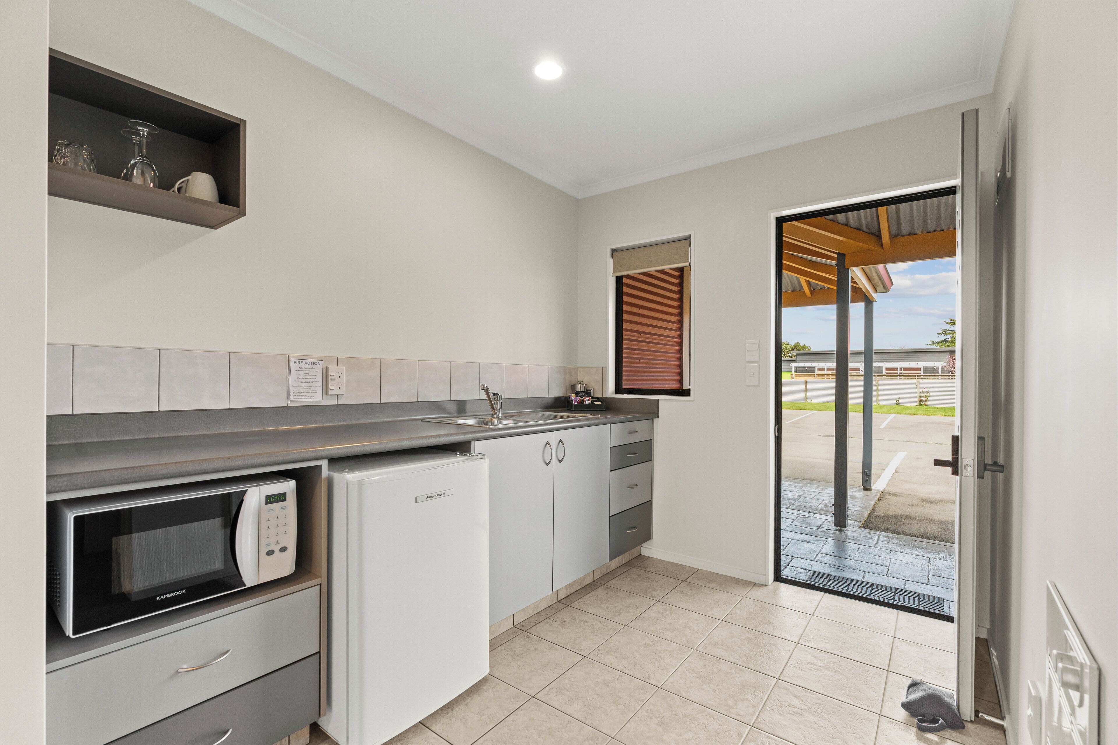 A modern kitchen with a built-in microwave, a sink, and a window with blinds.