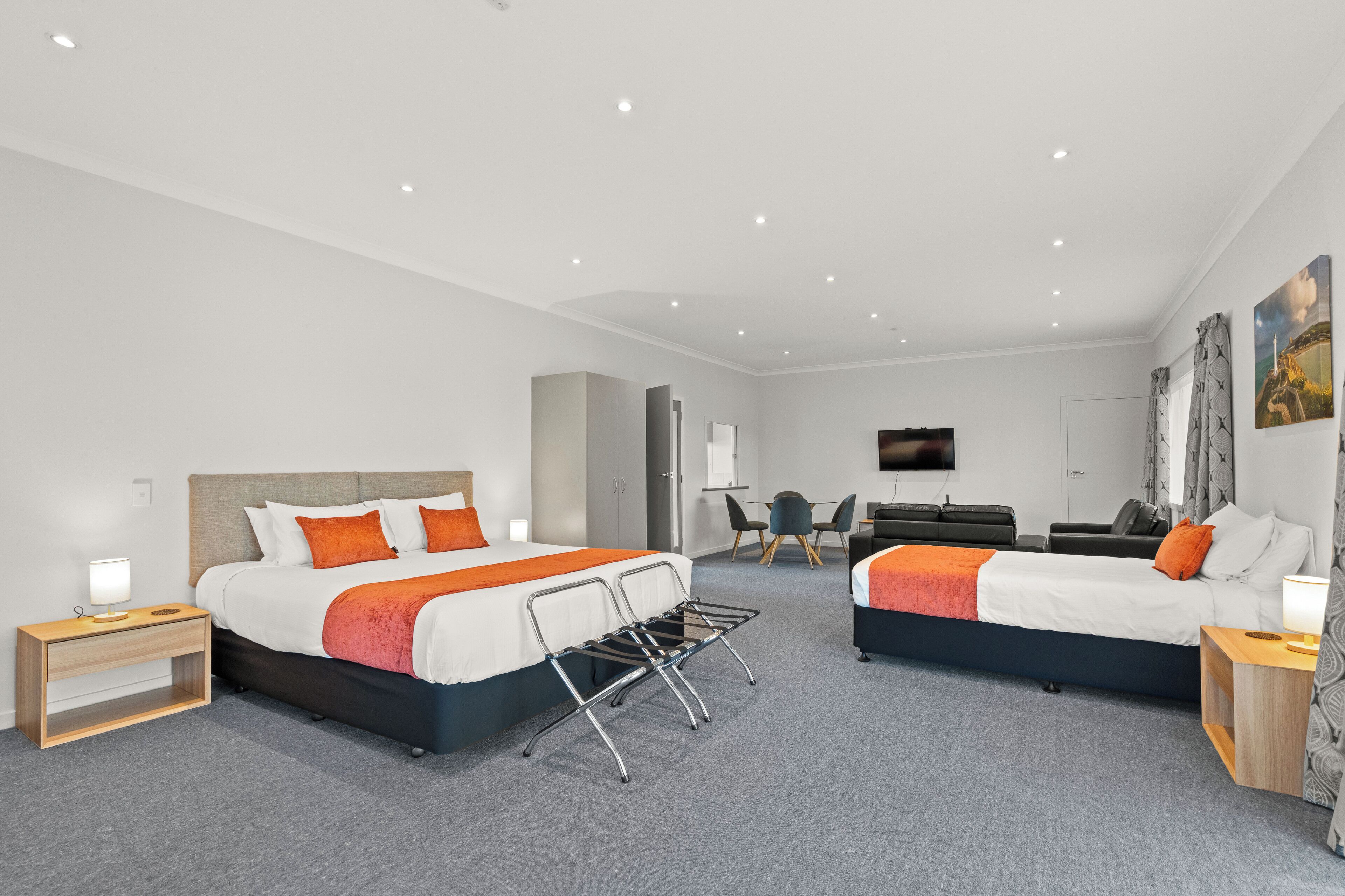 A modern hotel room with two beds, a desk, a chair, and a television.