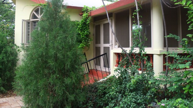 Una casa con techo rojo, un porche y una escalera que lleva a una puerta.