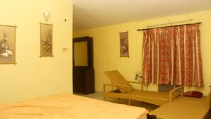 Una habitación con cama, una silla, ventilador de techo y ventana con cortinas.
