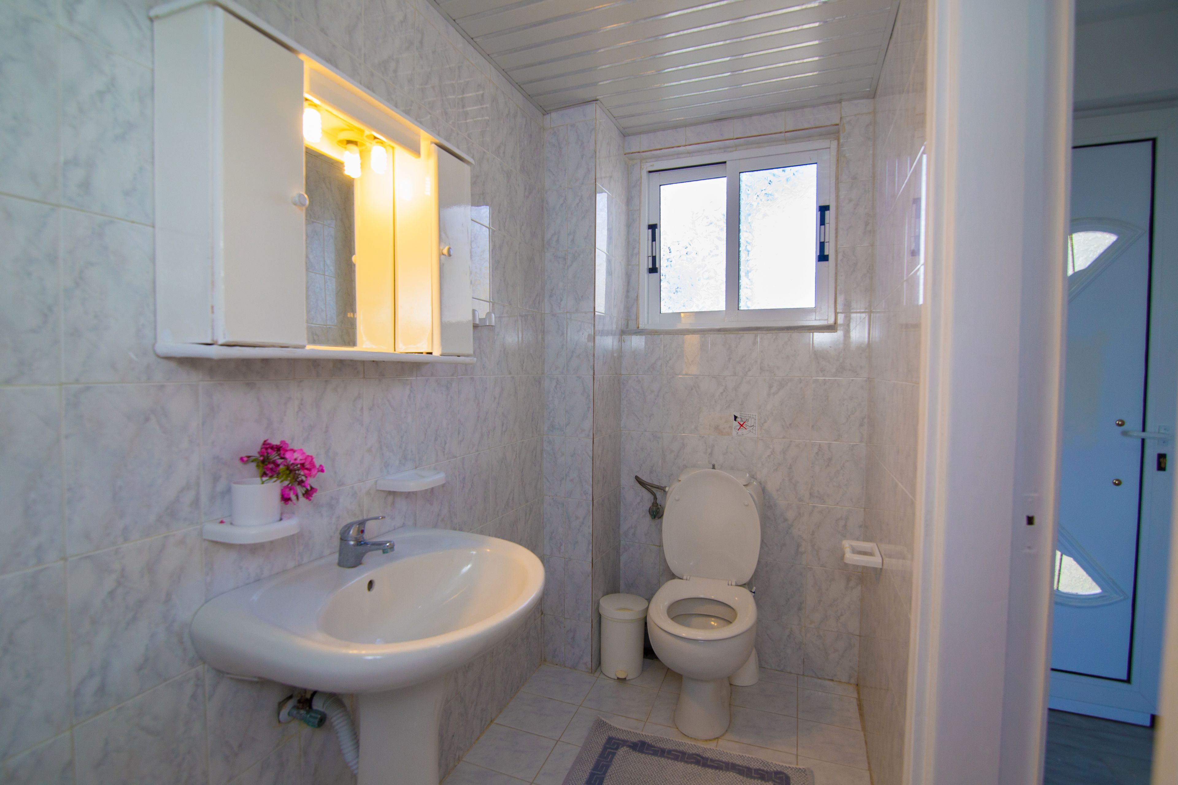 A bathroom with a sink, toilet, and a window.