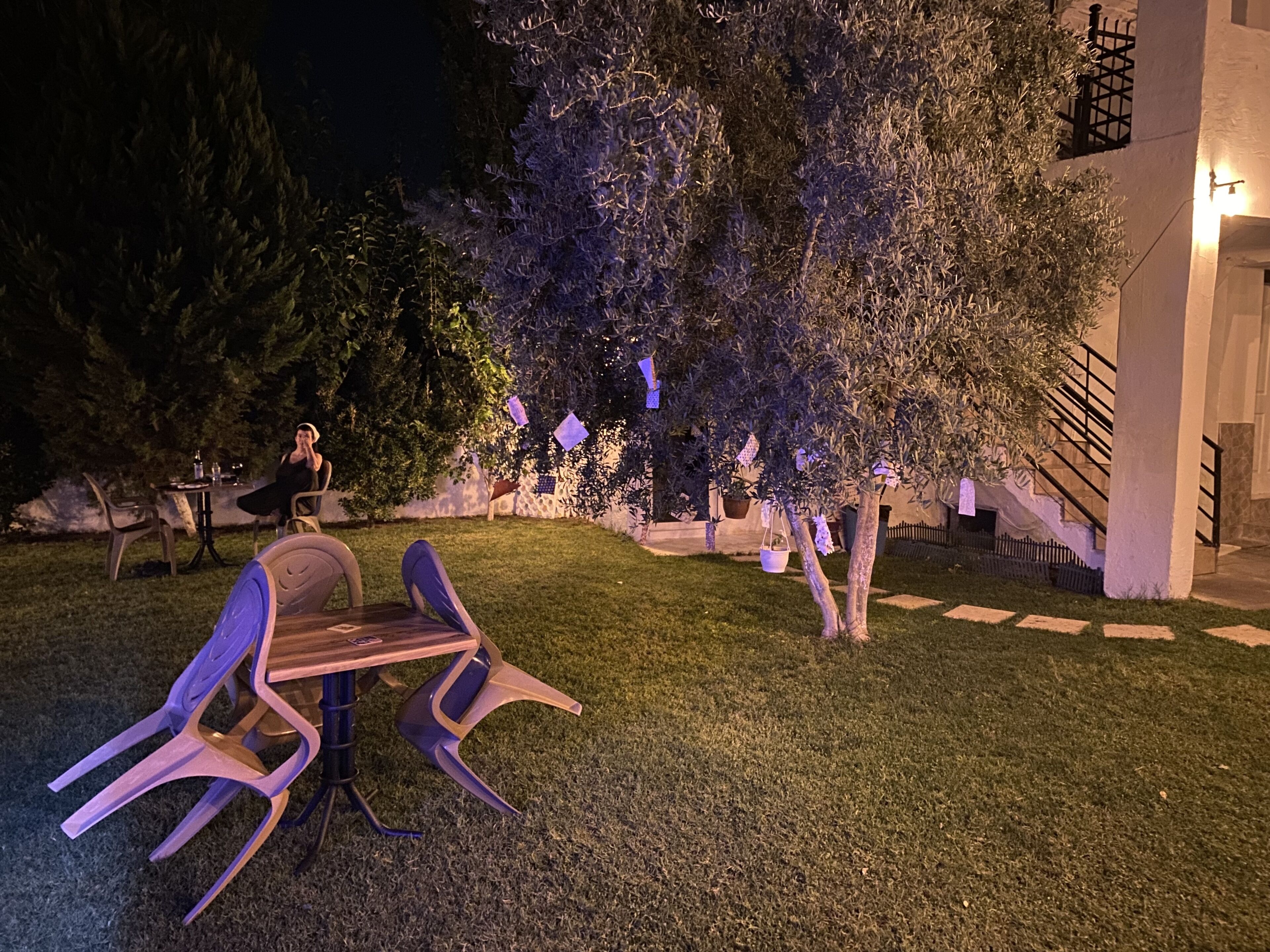 An outdoor seating area with a table and chairs, a tree, and a staircase leading to a building.