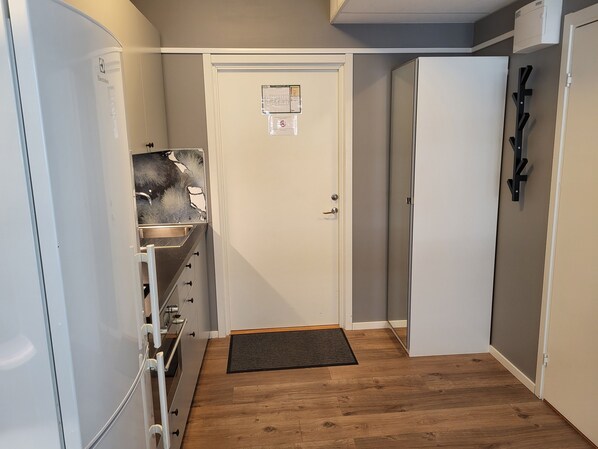 A narrow hallway with a wooden floor, a white door, and a small sink area. - Apartments Uppsala Portalgatan (Uppsala)