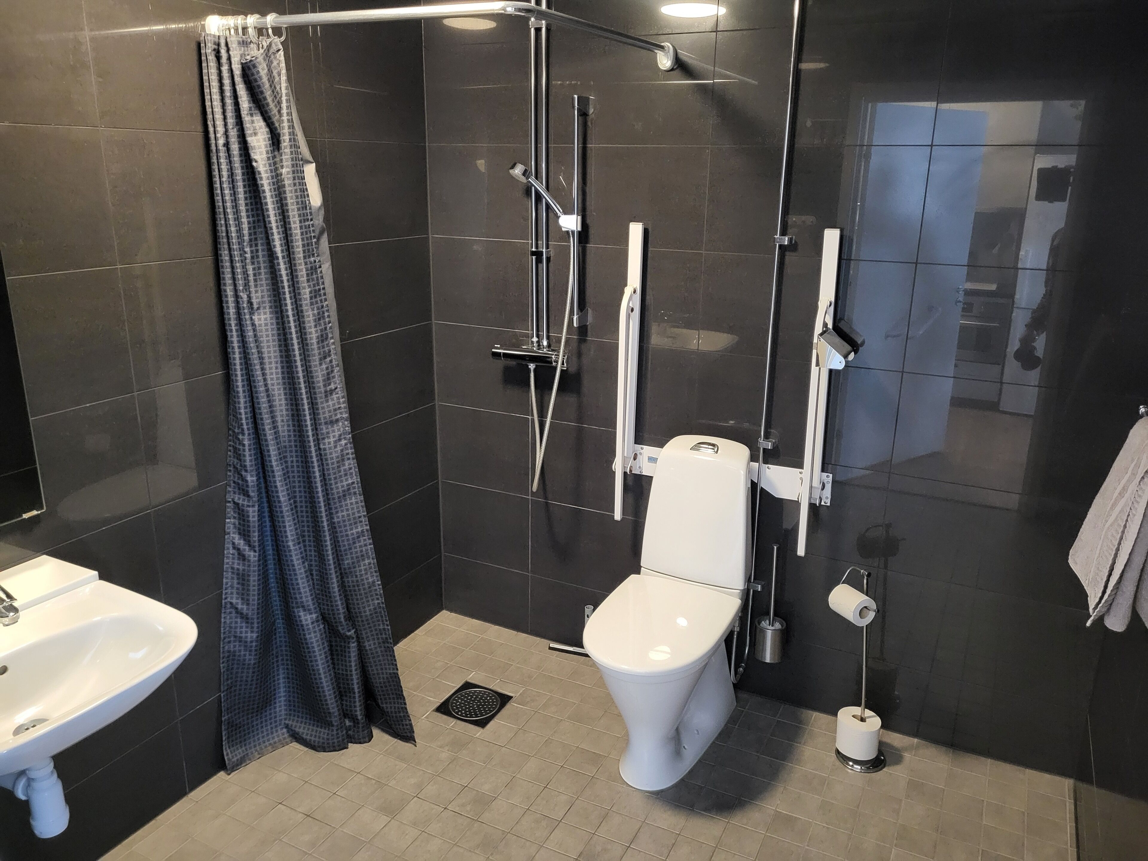 A modern bathroom with a shower, toilet, sink, and a towel rack.