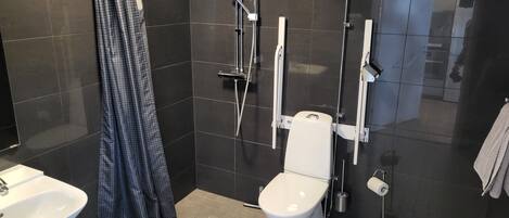A modern bathroom with a shower, toilet, sink, and a towel rack.
