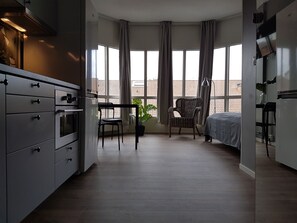 Eine moderne Küche mit eingebauten Geräten, ein Essbereich mit Stuhl und Tisch sowie ein großes Fenster mit Vorhängen.