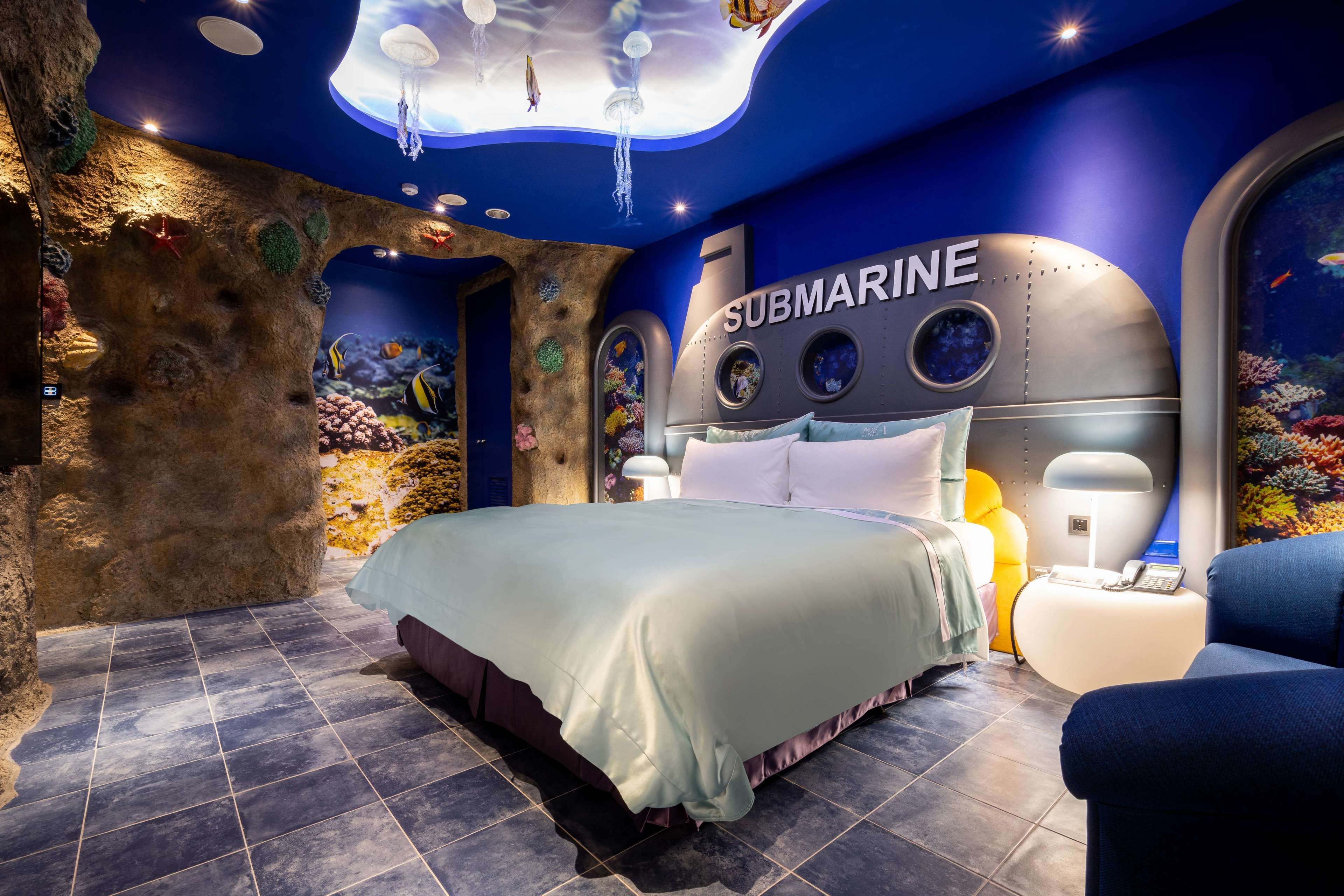 A submarine-themed bedroom with a bed, nightstands, and a large window.