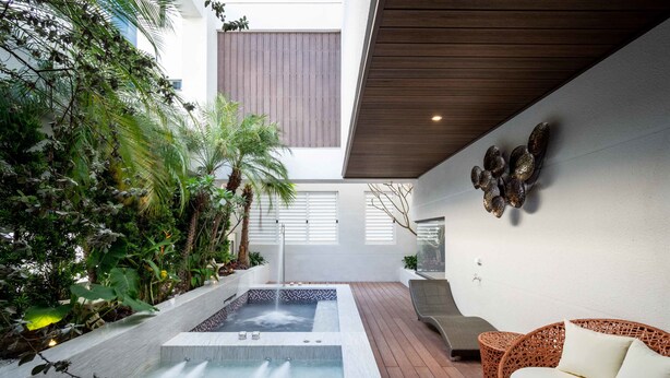 A modern outdoor spa area with a hot tub, wicker seating, and lush greenery. - Aurora Motel (Taichung)