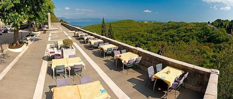 An outdoor dining area with tables and chairs, overlooking a scenic landscape.
