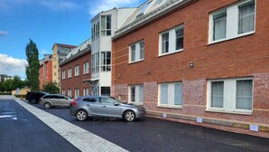A row of red brick buildings with multiple windows, a paved sidewalk, and parked cars. - Vandrarhem Uppsala Portalgatan - Hostel (Uppsala)