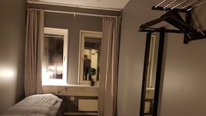 A bedroom with a bed, a dresser, a mirror, and a window with curtains. - Vandrarhem Uppsala Portalgatan - Hostel (Uppsala)