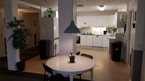 A modern kitchen with white cabinets, a central island, and a dining area with a round table and chairs. - Vandrarhem Uppsala Portalgatan - Hostel (Uppsala)