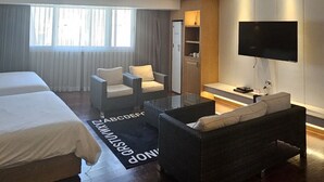 A modern hotel room with a large bed, a sofa, a TV, and a minibar. - Hotel Artheim (Gwangju)