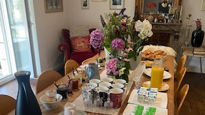 A dining table set for breakfast with plates, cutlery, and various food items. - Villa Tourelle (Dinan)