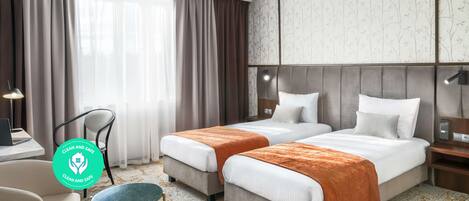 Una habitación de hotel con dos camas, un escritorio, una silla y una mesita.