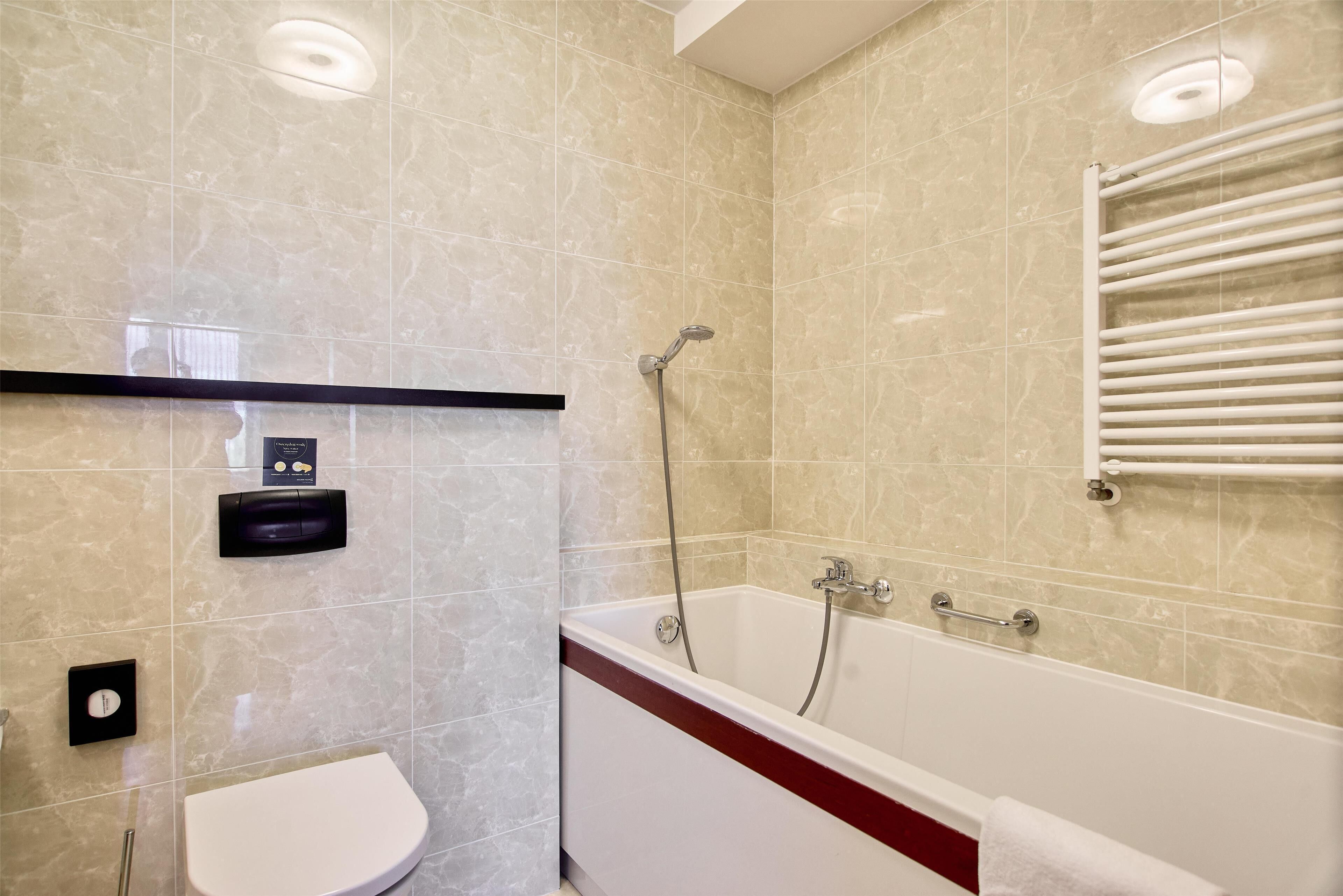 Een badkamer met een badkuip, toilet en een handdoekhouder.