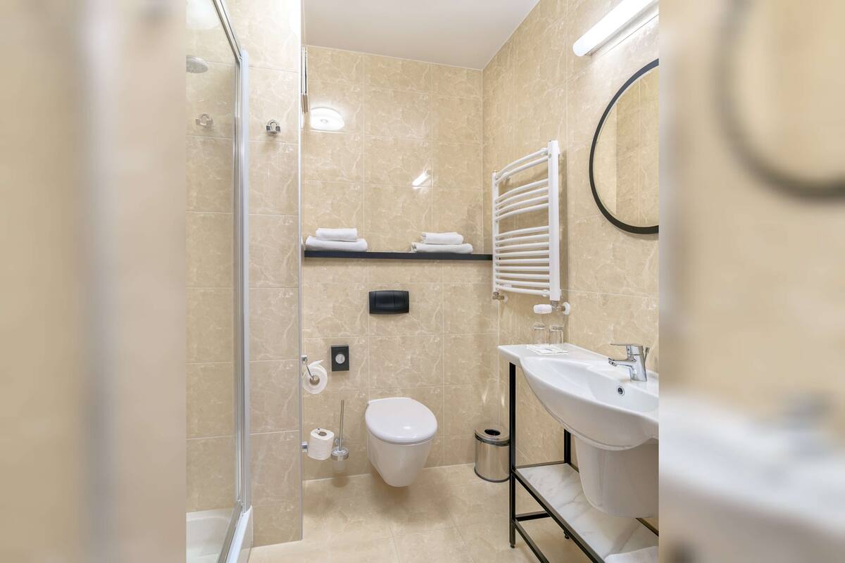 A modern bathroom with a glass shower enclosure, a toilet, a sink, and a towel rack.