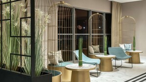Un área de estar moderna con asientos, mesas y plantas decorativas.