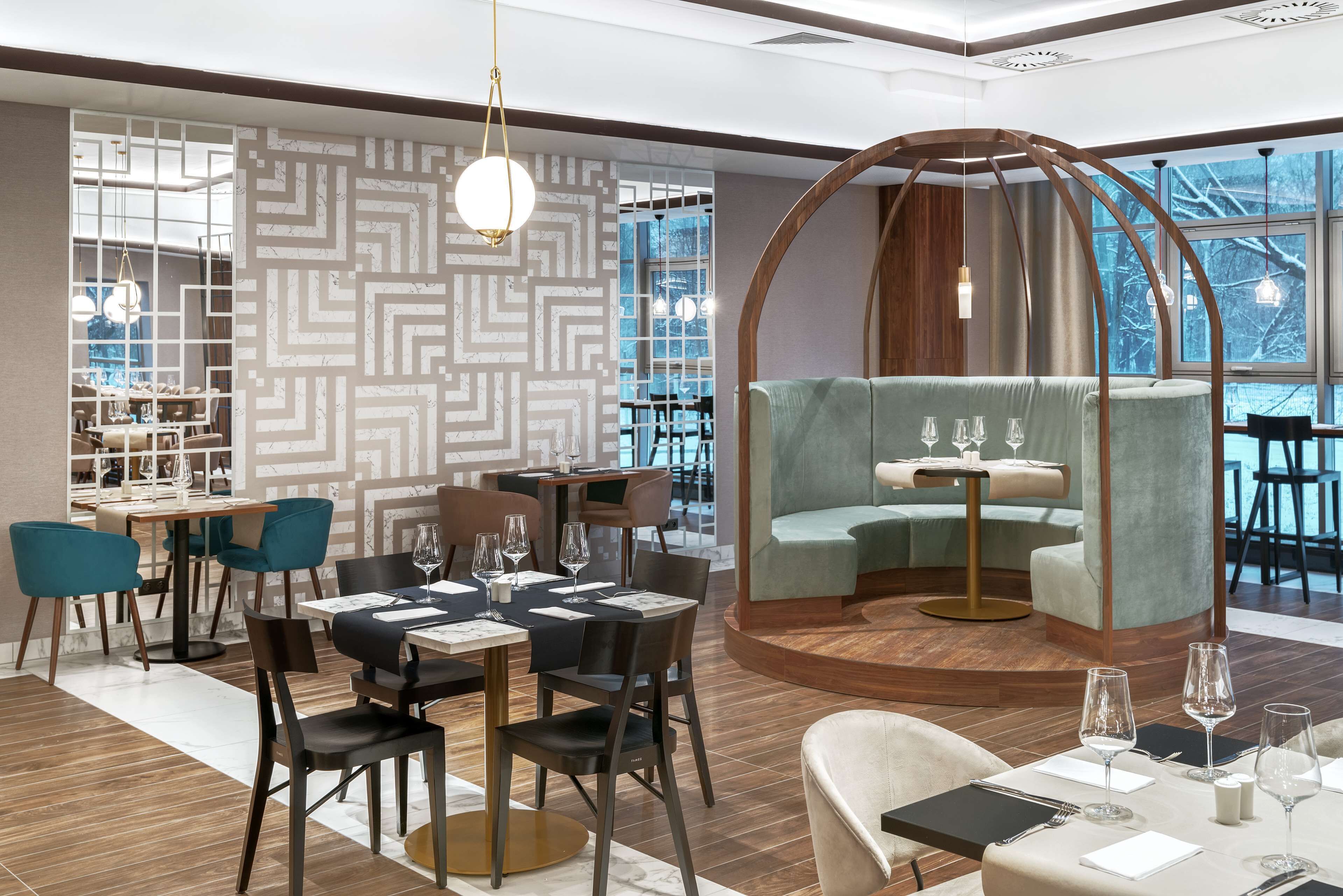 A modern dining area with a round table, chairs, and a seating nook with a cushioned bench.